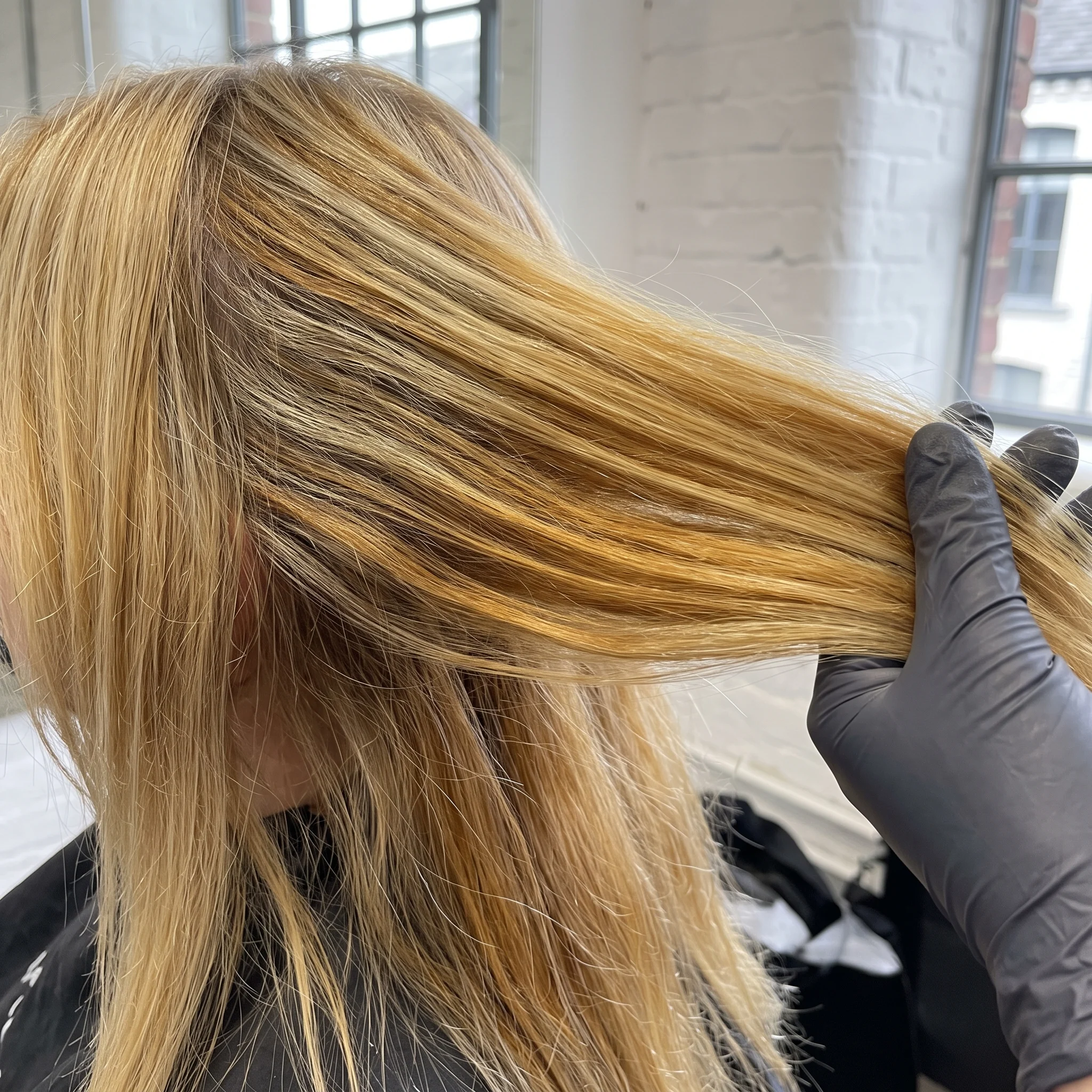 The same blonde before correction: brassy yellow-orange lengths with a hard dark band at the roots